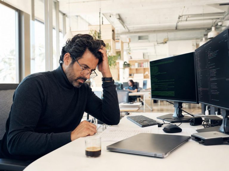 Homme stressé devant écrans d’ordinateur au bureau