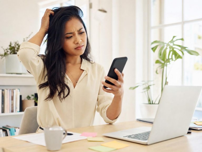Femme perplexe regardant son smartphone au bureau